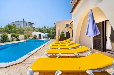 a row of yellow lounge chairs next to a swimming pool at Villa Palmeiras - Serene Private Villa in Albufeira