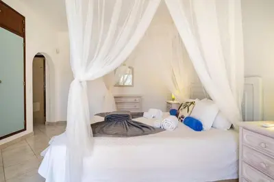 a bedroom with a white bed with a canopy at Villa Palmeiras - Serene Private Villa in Albufeira
