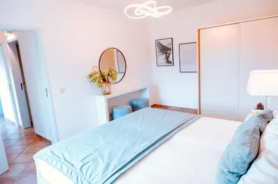 a white bedroom with a bed and a mirror at Villa Angélica - Cozy Homestay in Albufeira