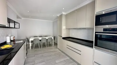 a kitchen with white cabinets and a table with chairs at Hibisco 1 by Check-in Portugal in Albufeira