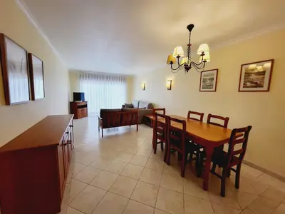 a dining room and living room with a table and chairs at Varandas do Sol by Garvetur in Vilamoura