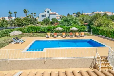 a large swimming pool with chairs and umbrellas at Villa Judite in Albufeira