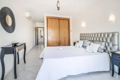 a bedroom with a large white bed and a table at Villa Judite in Albufeira
