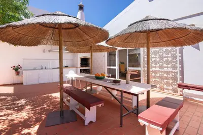 a patio with two large umbrellas and a table and chairs at Monte do Pataco in Albufeira