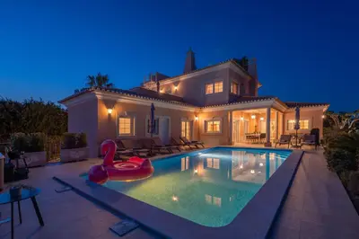 a large house with a swimming pool at night at Extraordinary Villa on an elevated position in Quinta do Lago in Quinta do Lago