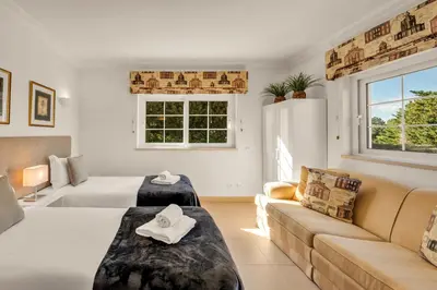 a living room with two beds and a couch at Extraordinary Villa on an elevated position in Quinta do Lago in Quinta do Lago