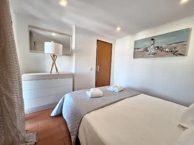 a white table and chair with a pool in the background at Casinha do sul- Private pool in Albufeira