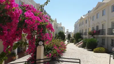 a street with pink flowers on the side of buildings at Old Village Vilamoura in Quarteira