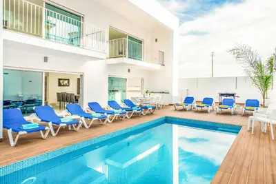 a villa with a swimming pool and blue chairs at Villa Aventura in Albufeira