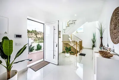 a white hallway with a door and stairs with plants at Villa Aventura in Albufeira