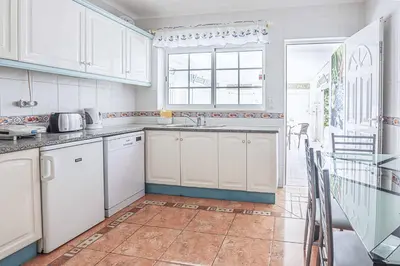 a kitchen with white cabinets and a window at Villa Vivienda Rosa in Albufeira