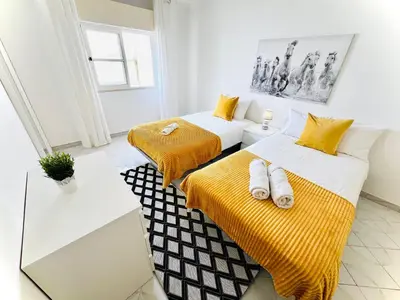 two beds in a room with yellow and white at Apartamento 5 Estrelas Praia da Oura in Albufeira