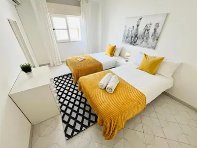 two beds in a room with yellow and white at Apartamento 5 Estrelas Praia da Oura in Albufeira