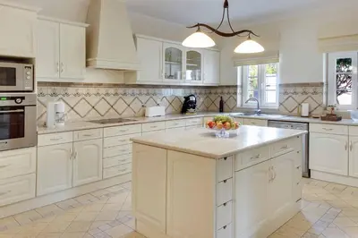 a kitchen with white cabinets and a bowl of fruit on a counter at Villa Lisianto in Albufeira
