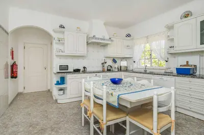 a kitchen with white cabinets and a table and chairs at Villa Cerrinho in Albufeira
