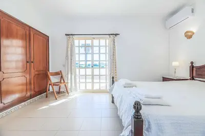 a bedroom with a bed and a chair and a window at Villa Natalia Sun in Albufeira