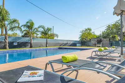 a swimming pool with two chairs and a table at Villa Dala in Albufeira