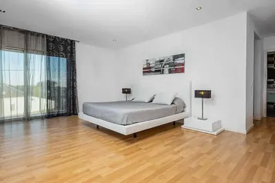 a white bedroom with a bed and a wooden floor at Villa Dala in Albufeira