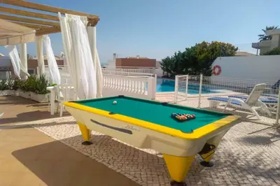 a pool table on a patio next to a swimming pool at Casa Oliveira in Albufeira