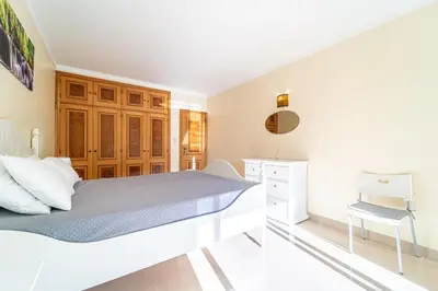 a white bedroom with a bed and a desk at Blue Horizon Apartment by HelloVacations in Albufeira