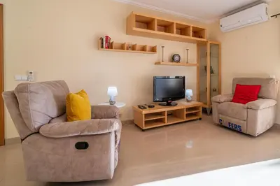 a living room with two chairs and a flat screen tv at Blue Horizon Apartment by HelloVacations in Albufeira