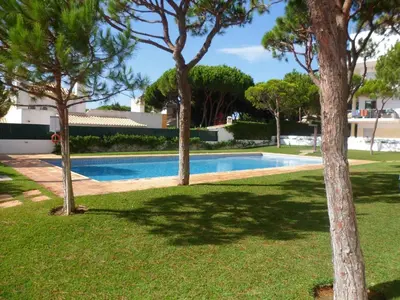 a swimming pool in a yard with trees around it at Jardins da Falesia in Albufeira
