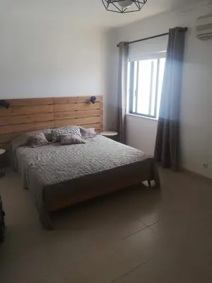 a bedroom with a bed with a wooden headboard and a window at Jardins da Falesia in Albufeira
