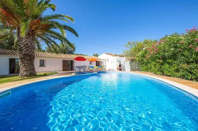 a table with a red umbrella next to a pool at Casa Nomanico in Estói