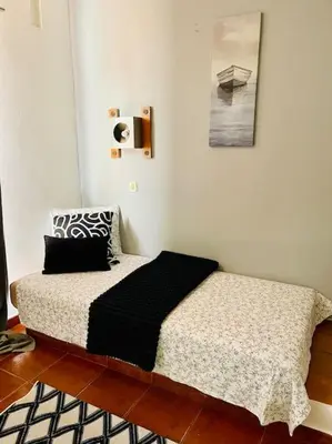 a bed in a white room with a black pillow at Resort Albufeira T2, Praia da Oura in Albufeira