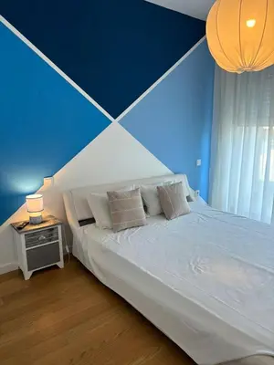 a bedroom with a large bed with a blue wall at The Albufeira Concierge - Prime Sunset Design in Albufeira