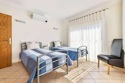 a bedroom with two beds and a chair at Villa Astro in Albufeira
