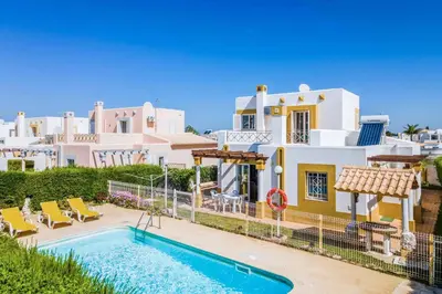 a villa with a swimming pool in front of a house at Villa Ninos in Albufeira