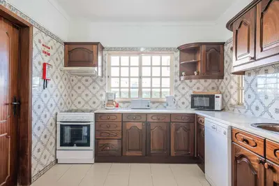 a kitchen with wooden cabinets and white appliances at Villa Noras in Albufeira