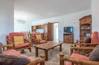 a living room with chairs and a table and a tv at Villa Noras in Albufeira