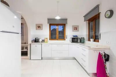 a white kitchen with white cabinets and a microwave at Villa Jacaranda Bordeira in Corotelo
