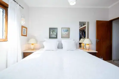 a bedroom with a large white bed with two lamps at Villa Jacaranda Bordeira in Corotelo