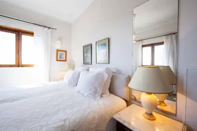 a white bedroom with a bed and a lamp at Villa Jacaranda Bordeira in Corotelo