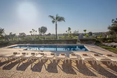 a pool with chaise lounge chairs and a group at Al Meida Guesthouse in Albufeira