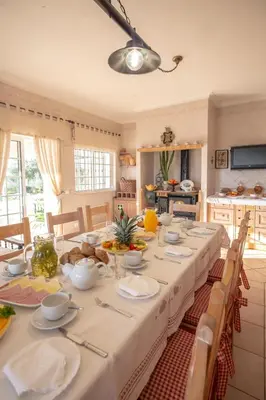 a dining room with a long table with white table cloth at Al Meida Guesthouse in Albufeira