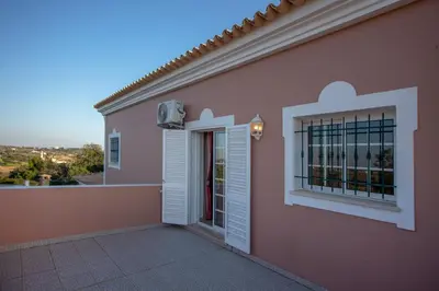 a pink house with a door and a window at Al Meida Guesthouse in Albufeira