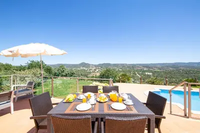 a dining table with chairs and an umbrella on a patio at Casa Salir in Salir