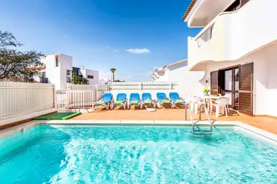 a swimming pool with blue chairs and a house at Villa Canto in Albufeira