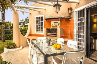 a patio with a glass table and white chairs at Villa Silveira II in Vilamoura