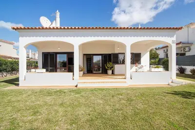 a white house with an archway in a yard at Villa Luísa Galé in Albufeira