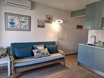 a living room with a blue couch in a kitchen at NORA Studio in Quarteira