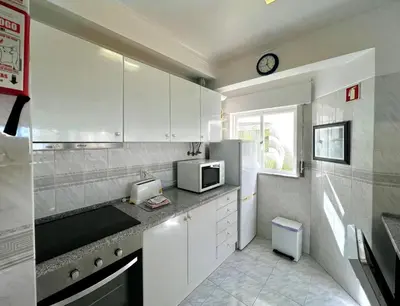 a kitchen with white cabinets and a clock on the wall at Albufeira Concept 2 With Pool by Homing in Galé
