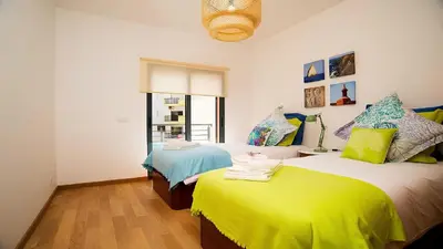 a bedroom with two beds and a window at Apartamento Oura Mar - By Dalma Portuguesa in Albufeira