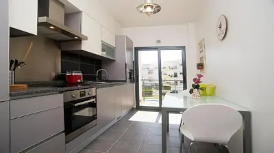 a kitchen with a table and a white chair at Apartamento Oura Mar - By Dalma Portuguesa in Albufeira