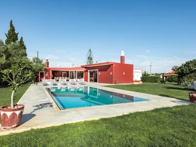 a swimming pool in front of a red house at Villa Recanto Murta V6 VIP Properties by Interhome in Azinhal