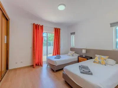 a bedroom with two beds and a window with red curtains at Holiday Home Camélias VIP Properties by Interhome in Albufeira
